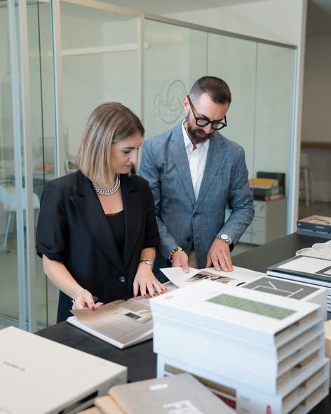 Due consulenti sfogliano un libro di progetti di architettura