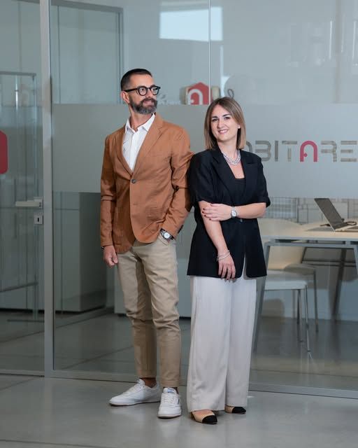 Il team di Abitare in ufficio, davanti alla vetrata con il logo